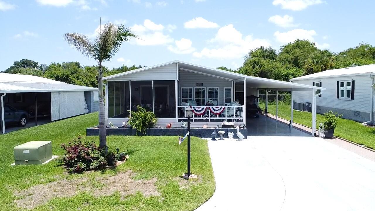 A manufactured home with a screened-in porch, carport, and palm tree on a grassy lot — 1529 SW 35th Circle, Okeechobee FL 34974, OKEECHOBEE, FL