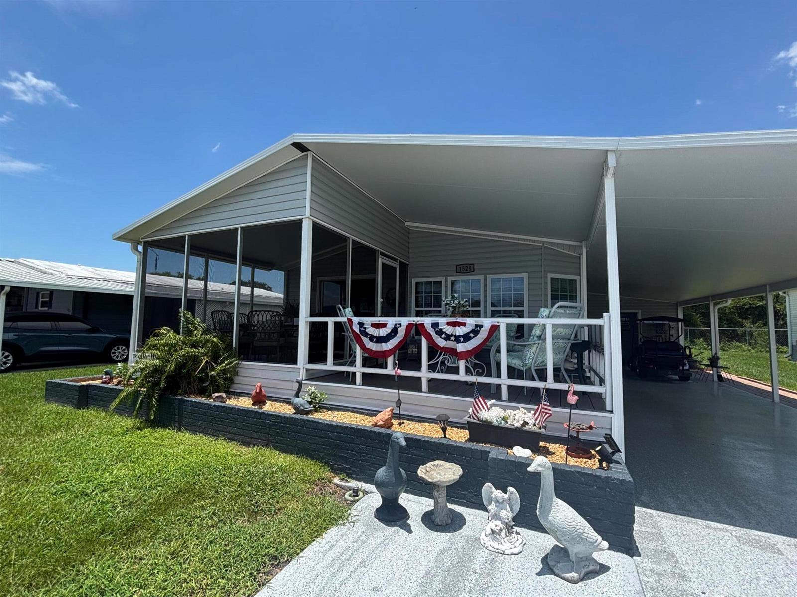 A manufactured home features a screened-in porch, a carport, and decorative lawn ornaments — 1529 SW 35th Circle, Okeechobee FL 34974, OKEECHOBEE, FL