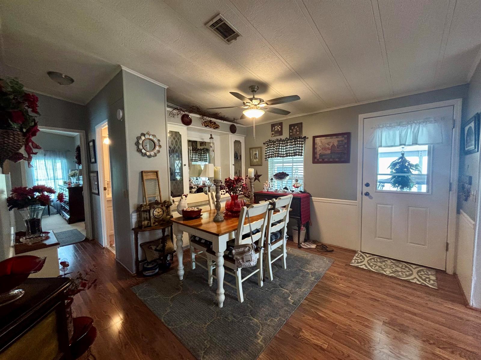 A dining area features a wooden table, white chairs, a rug, and a front door — 1529 SW 35th Circle, Okeechobee FL 34974, OKEECHOBEE, FL