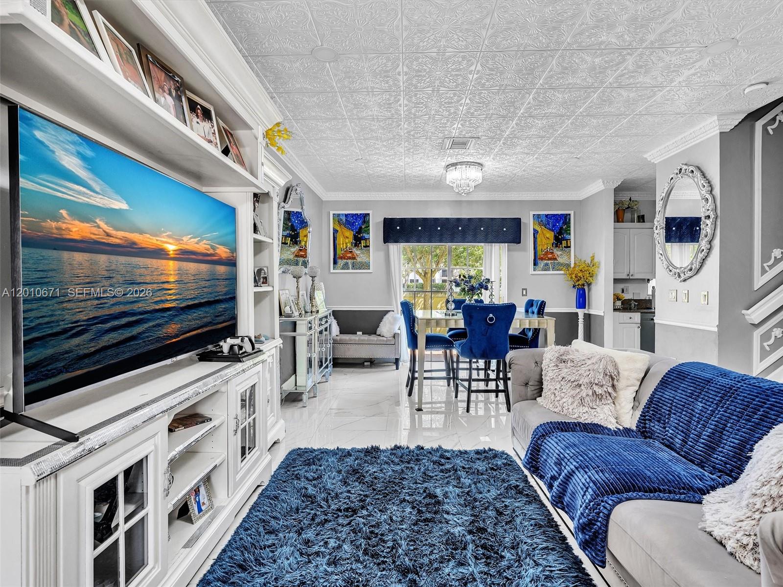 A living and dining area features a patterned ceiling, blue accents, and a large television — 7659 N Stonecreek Cir, Davie FL 33024, DAVIE, FL