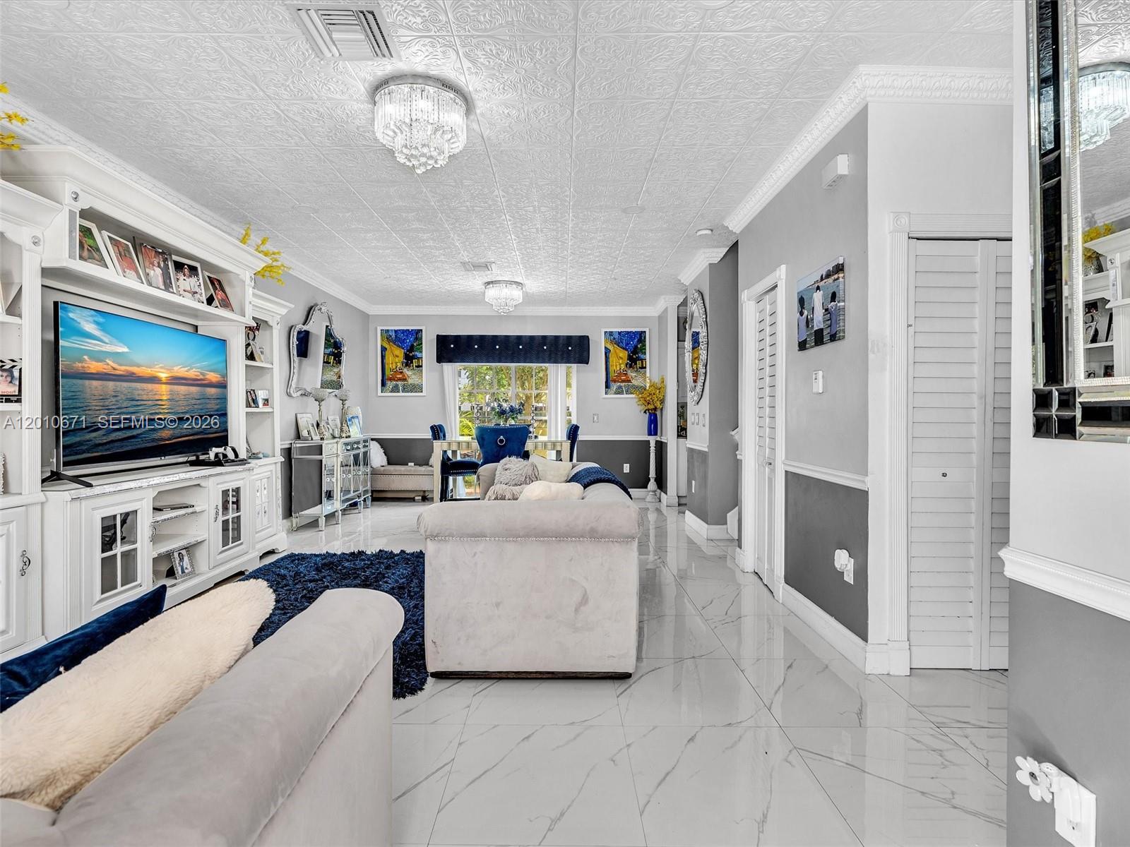 A living room features a white entertainment center, gray walls, tiled floors, and a textured ceiling — 7659 N Stonecreek Cir, Davie FL 33024, DAVIE, FL