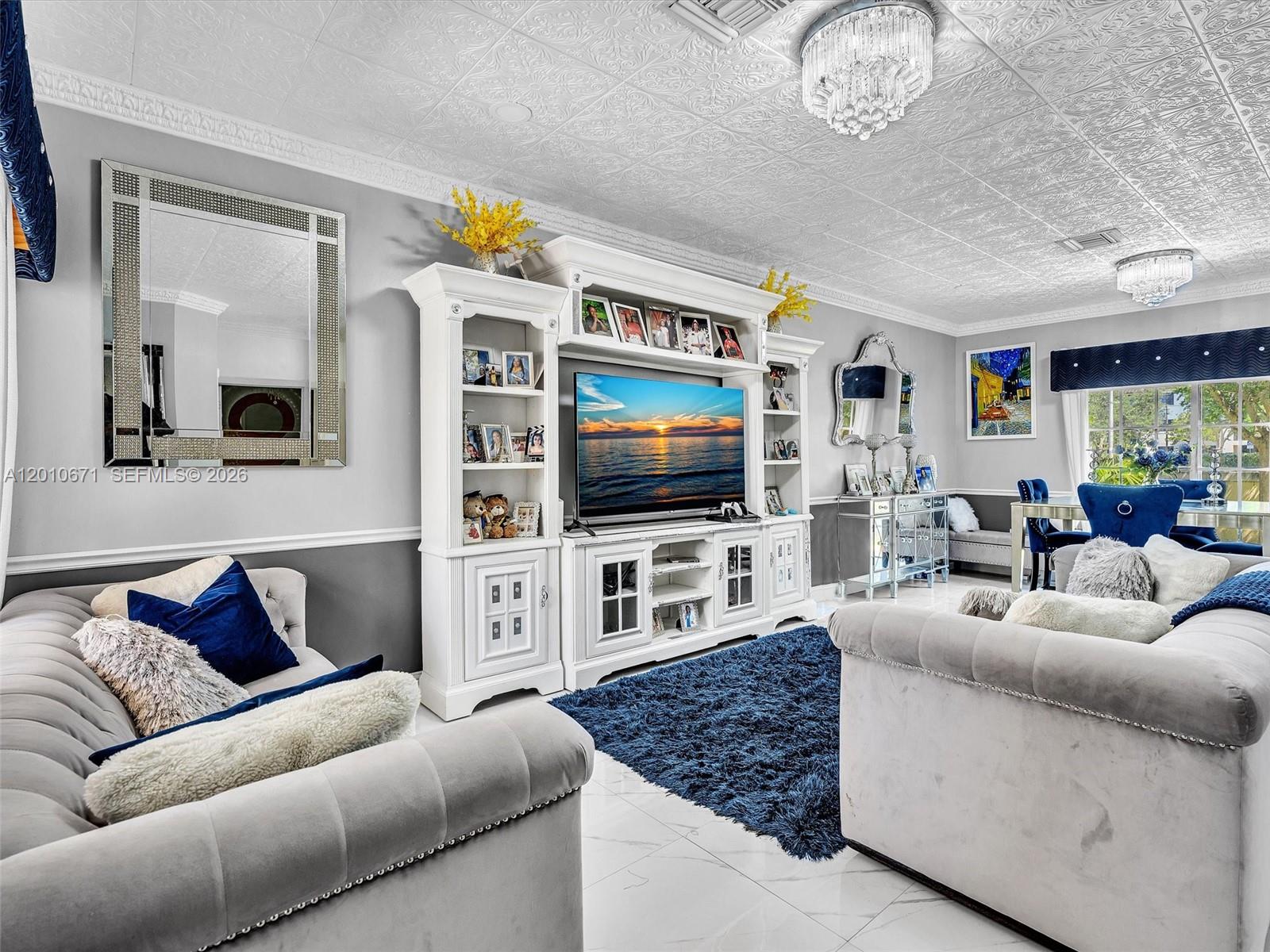 A living room features gray tufted sofas, a white entertainment center, and a blue rug — 7659 N Stonecreek Cir, Davie FL 33024, DAVIE, FL