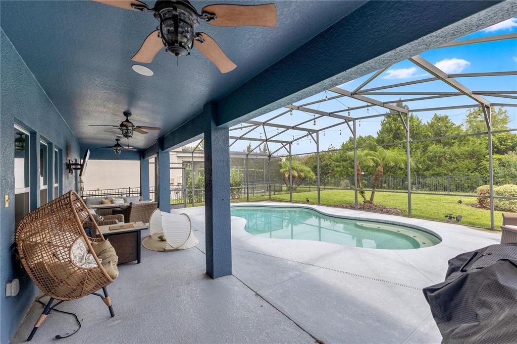 A covered patio with ceiling fans overlooks a swimming pool enclosed by a screen cage — 5233 VILLA ROSA AVENUE, ST CLOUD, FL