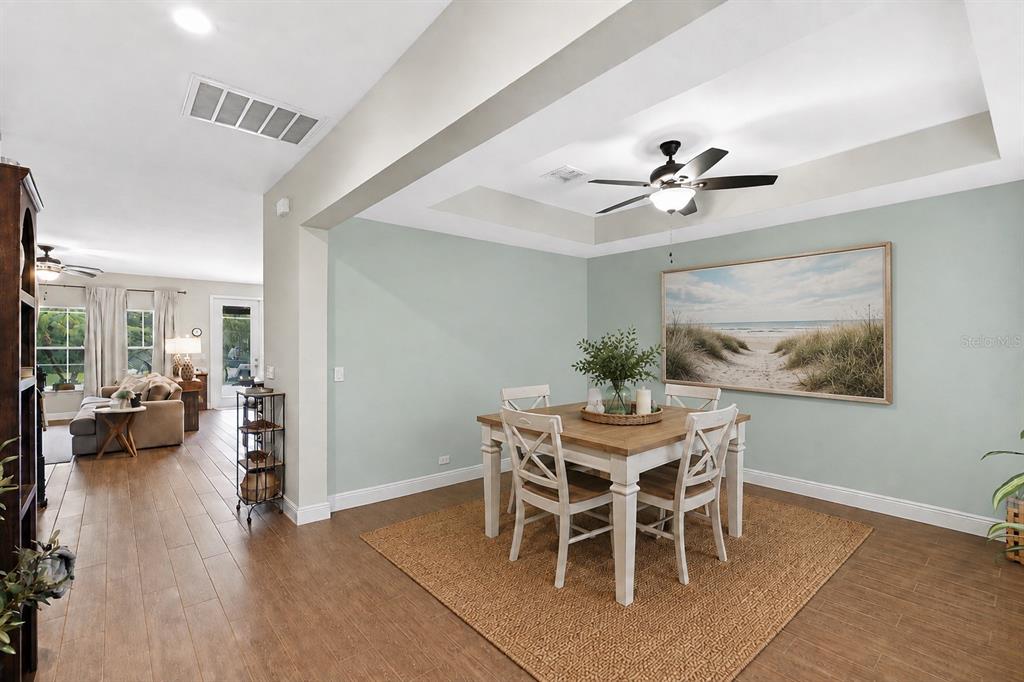 A dining area with a tray ceiling, ceiling fan, and a square table on a rug — 5233 VILLA ROSA AVENUE, ST CLOUD, FL