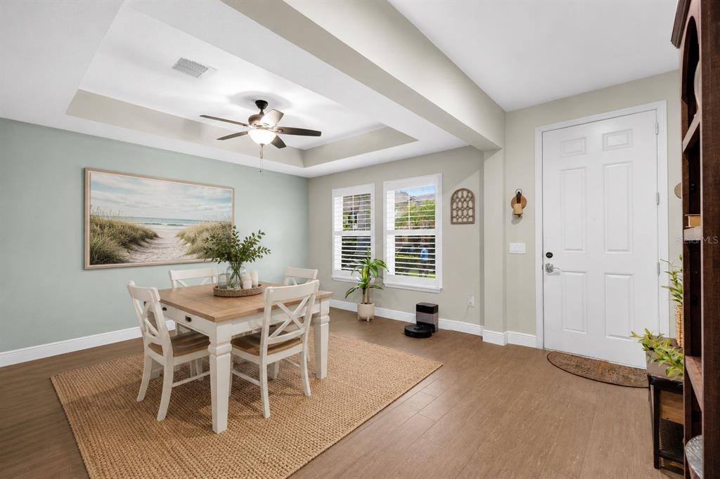 A dining area with a tray ceiling, light wood floors, and a white front door — 5233 VILLA ROSA AVENUE, ST CLOUD, FL