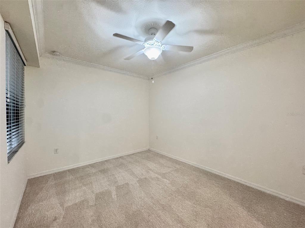An empty bedroom features beige carpet, white walls, and a ceiling fan with lights — 17118 VARDON TERRACE UNIT 303, BRADENTON, FL