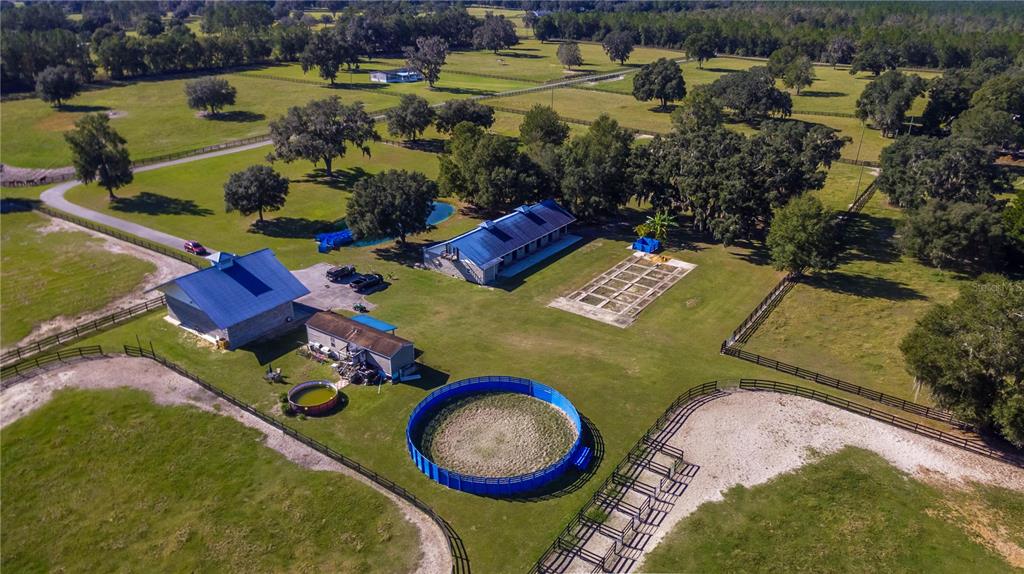 An aerial view shows a rural property with a house, barn, round pen, and pastures — 7787 NW 150TH AVENUE, MORRISTON, FL