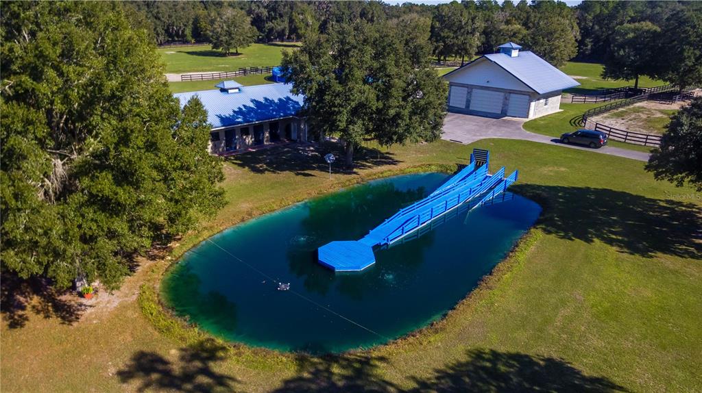An aerial view shows a blue dock extending into a pond near two outbuildings — 7787 NW 150TH AVENUE, MORRISTON, FL