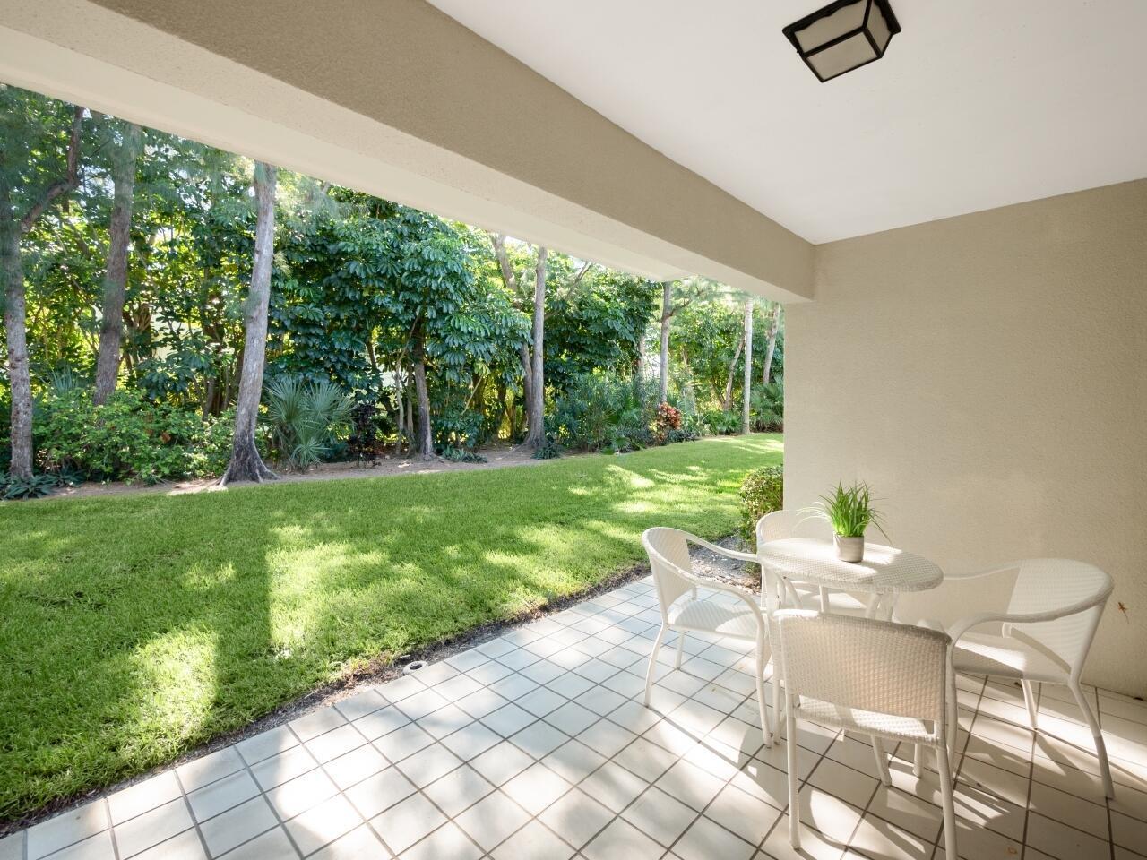A covered patio with tiled flooring, a small dining set, and a view of a lawn — 1262 Sugar Sands Boulevard, West Palm Beach FL 33404, WEST PALM BEACH, FL