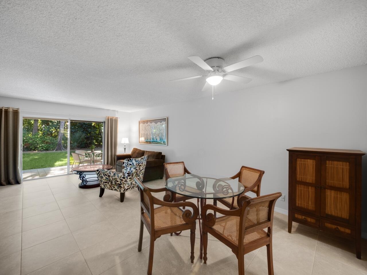 A dining area with a glass table and chairs sits in an open-concept living space — 1262 Sugar Sands Boulevard, West Palm Beach FL 33404, WEST PALM BEACH, FL