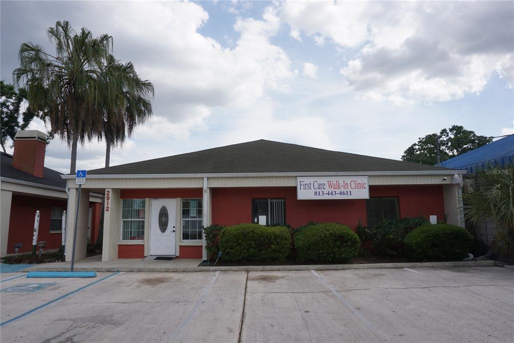A red-walled commercial building with a white door and a walk-in clinic sign — 2910 & 2912 W WATERS AVENUE, TAMPA, FL