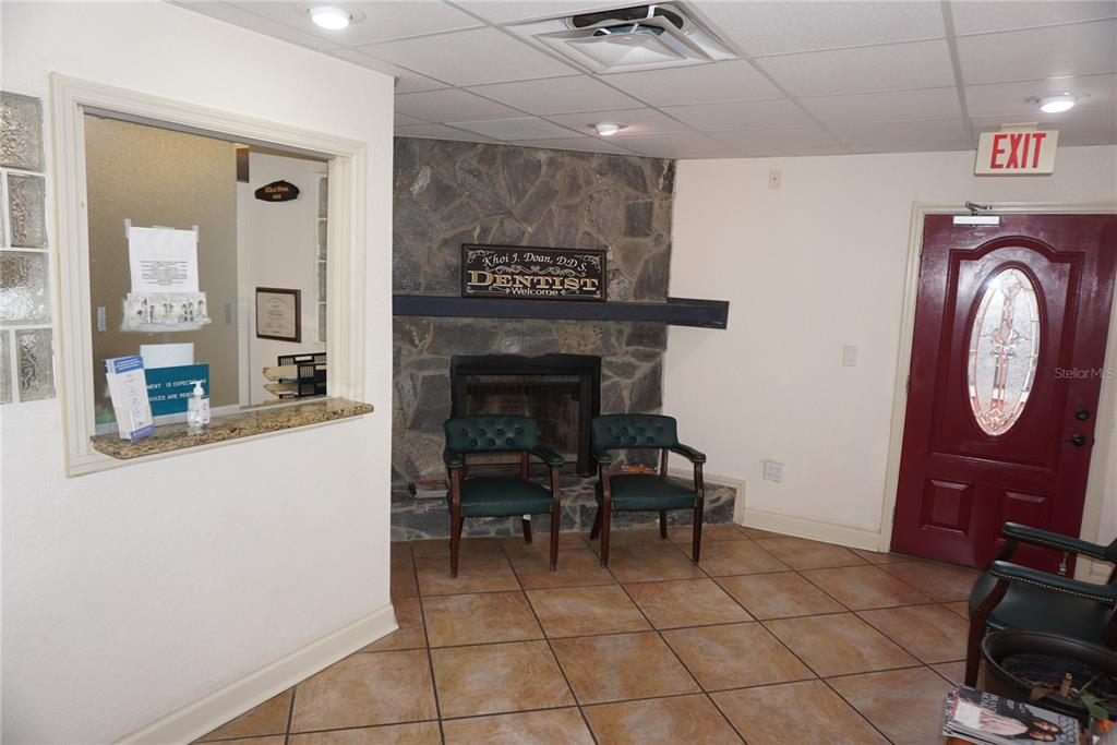 A dental office waiting room features a stone fireplace, tile flooring, and a red door — 2910 & 2912 W WATERS AVENUE, TAMPA, FL