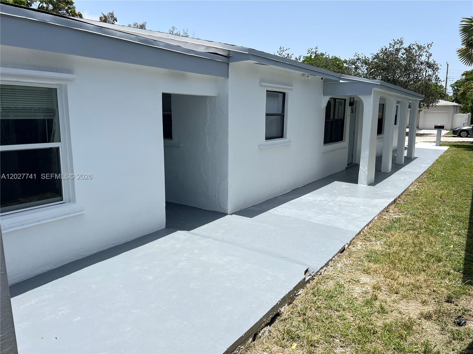 The exterior of a white, single-story house features a gray painted porch and walkway — 2226 Cody St, Hollywood FL 33020, HOLLYWOOD, FL