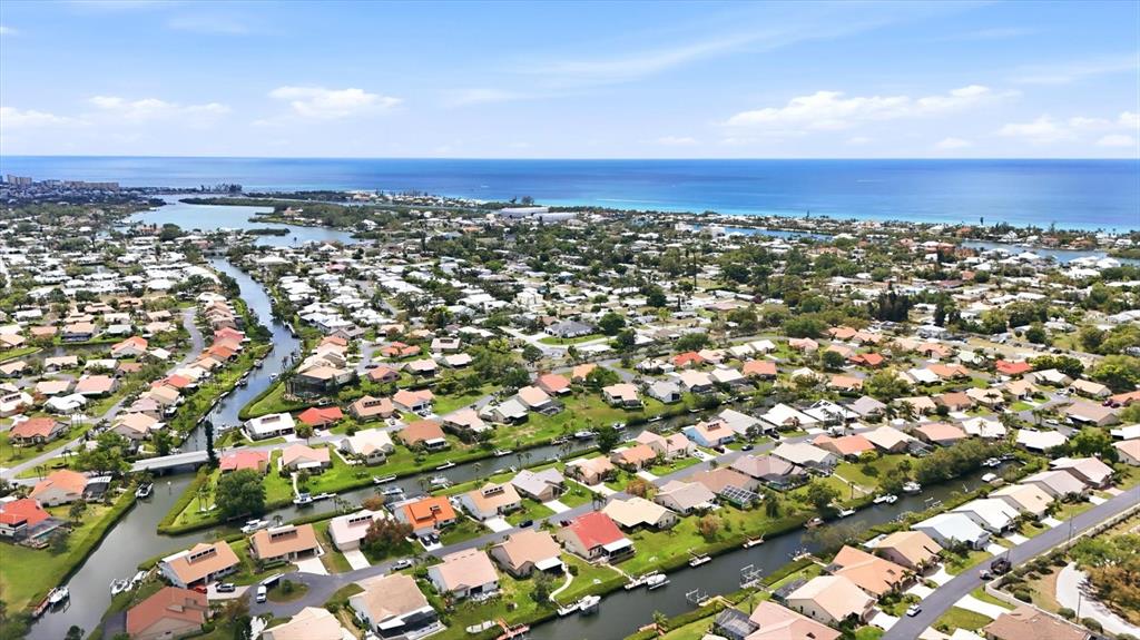 An aerial view shows a residential neighborhood with houses situated along winding canals near the ocean — 140 INLETS BOULEVARD UNIT 140, NOKOMIS, FL