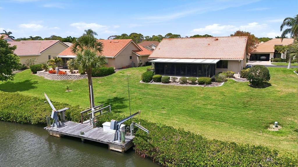 An aerial view shows a house with a tiled roof, a lawn, and a wooden dock — 140 INLETS BOULEVARD UNIT 140, NOKOMIS, FL