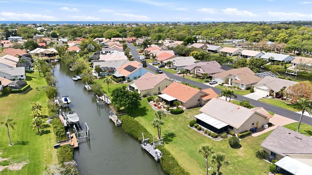 An aerial view shows houses along a canal with private boat docks and lush landscaping — 140 INLETS BOULEVARD UNIT 140, NOKOMIS, FL