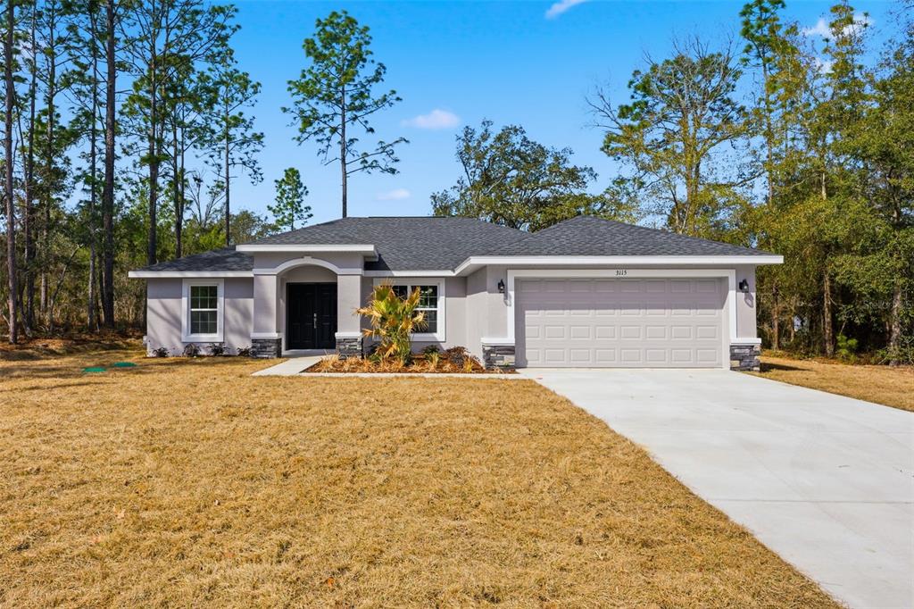 A single-story house with a gray stucco exterior, a dark roof, and a two-car garage — 3115 W FAIRBANK DRIVE, CITRUS SPRINGS, FL