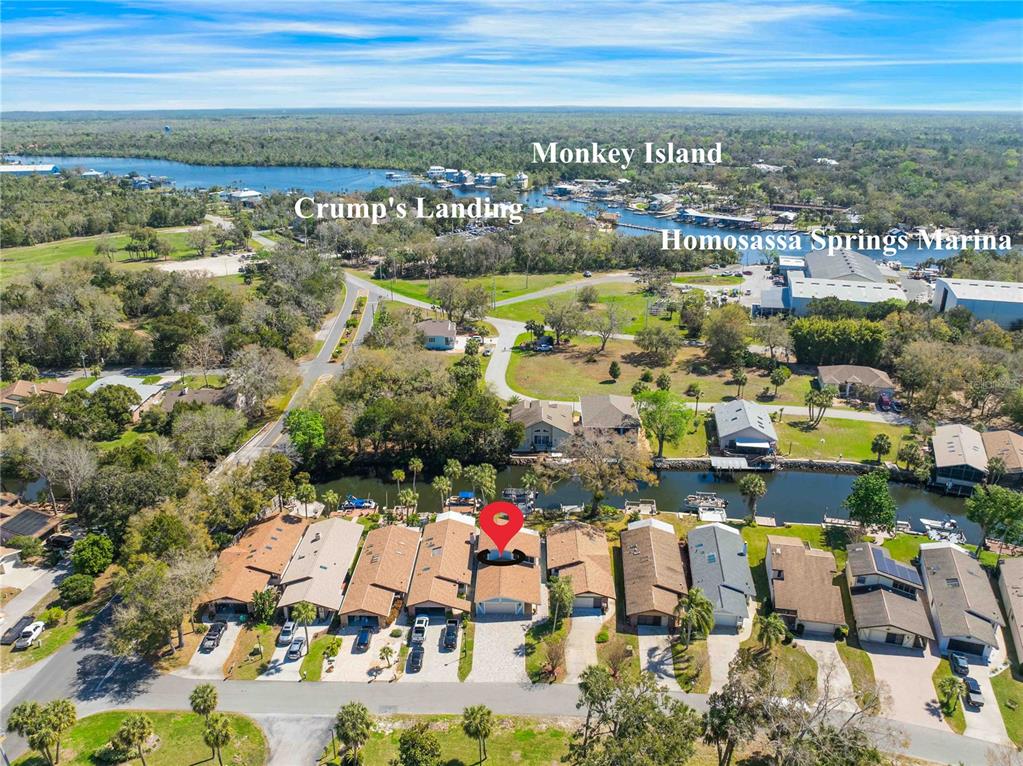This aerial view shows a residential neighborhood with a canal and nearby marina — 11436 W CLUBVIEW DRIVE, HOMOSASSA, FL
