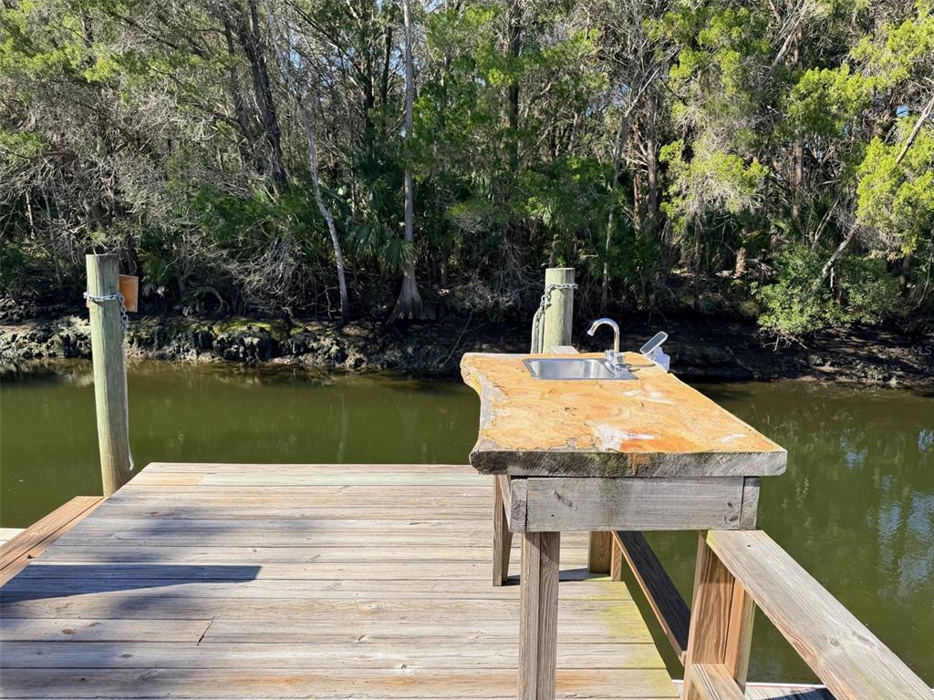 A wooden dock features a rustic live-edge cleaning station with a stainless steel sink — 12 PALM DRIVE, YANKEETOWN, FL