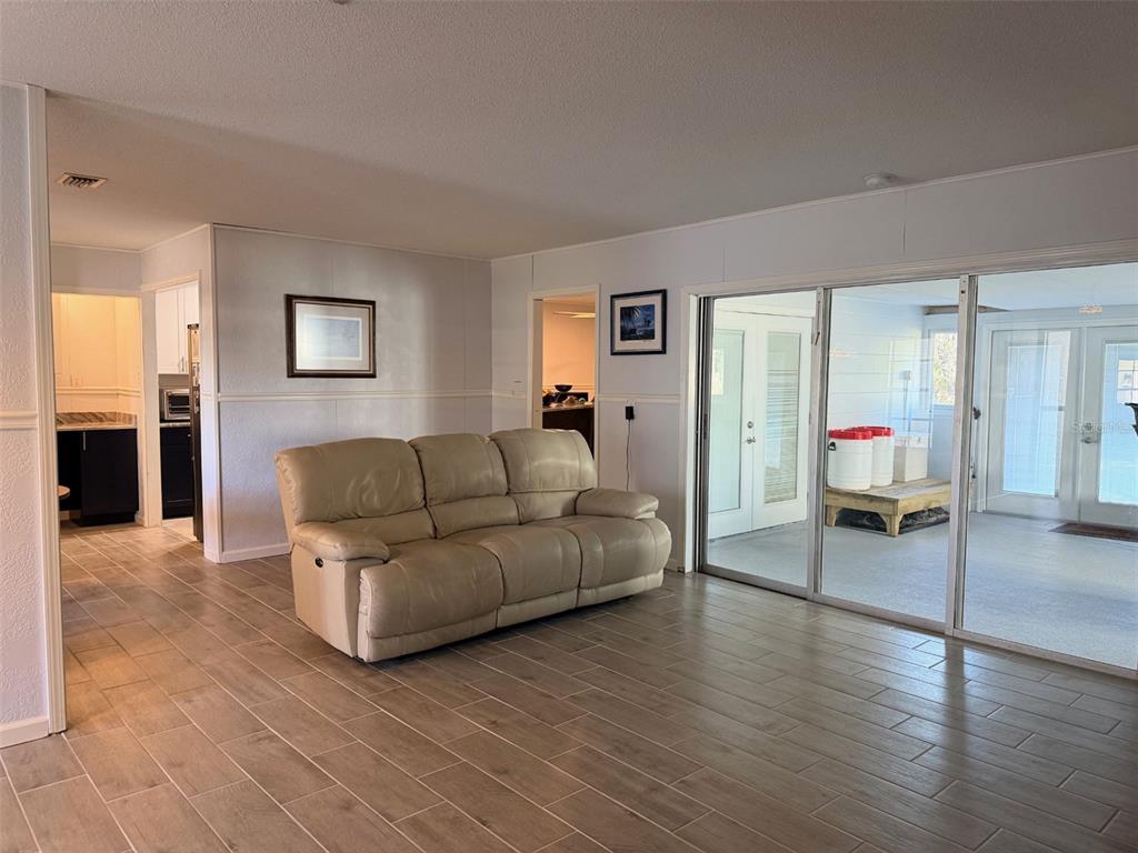 A living room with light-colored tile flooring, a beige sofa, and sliding glass doors — 12 PALM DRIVE, YANKEETOWN, FL