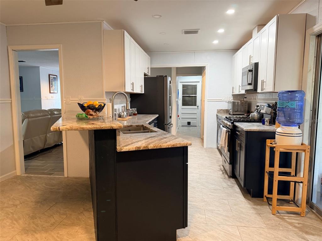 A kitchen features dark lower cabinets, white upper cabinets, granite countertops, and a peninsula island — 12 PALM DRIVE, YANKEETOWN, FL