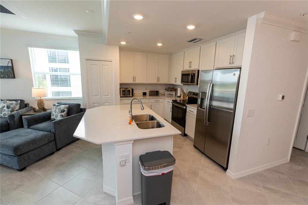 A kitchen with white cabinets, stainless steel appliances, and a central island with a sink — 15375 GREEN ACRES AVENUE UNIT 2228, PUNTA GORDA, FL
