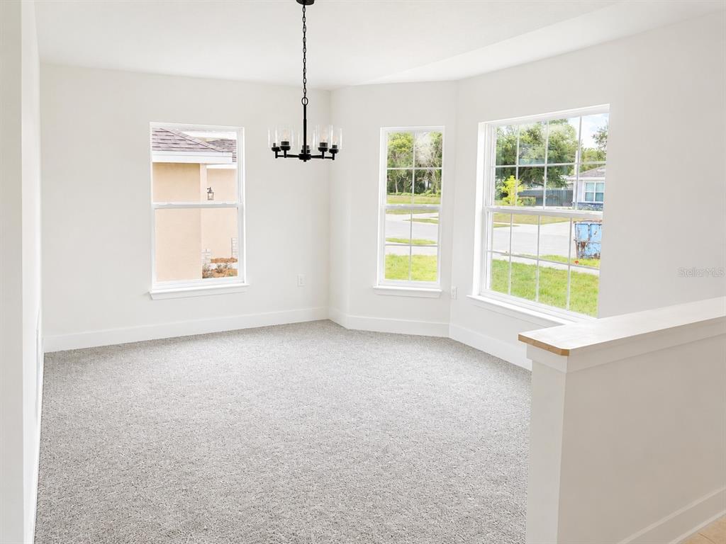 A dining area with gray carpet, white walls, a black chandelier, and three windows — 1643 ANN ROSE WAY, LEESBURG, FL