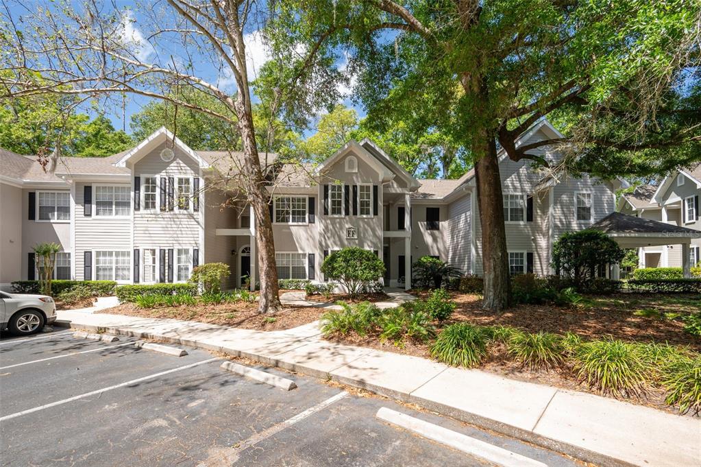A two-story apartment building with light gray siding, dark shutters, and a paved parking lot — 10000 SW 52ND AVENUE UNIT 188, GAINESVILLE, FL