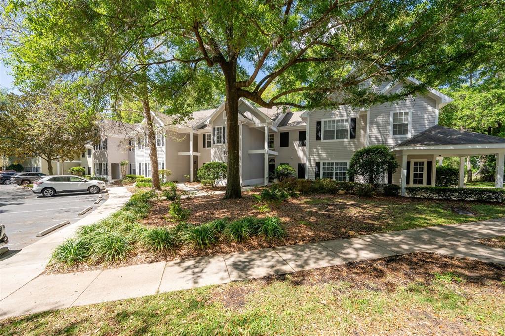 A multi-story apartment building with light gray siding is surrounded by trees and landscaping — 10000 SW 52ND AVENUE UNIT 188, GAINESVILLE, FL