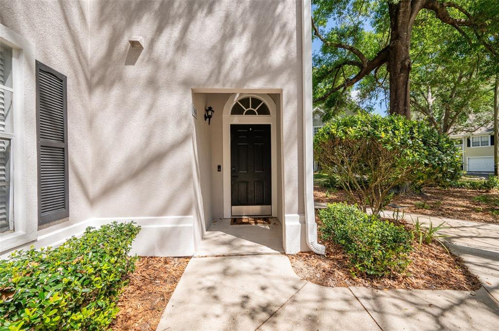 A beige stucco house exterior features a black front door with a semi-circular transom window — 10000 SW 52ND AVENUE UNIT 188, GAINESVILLE, FL