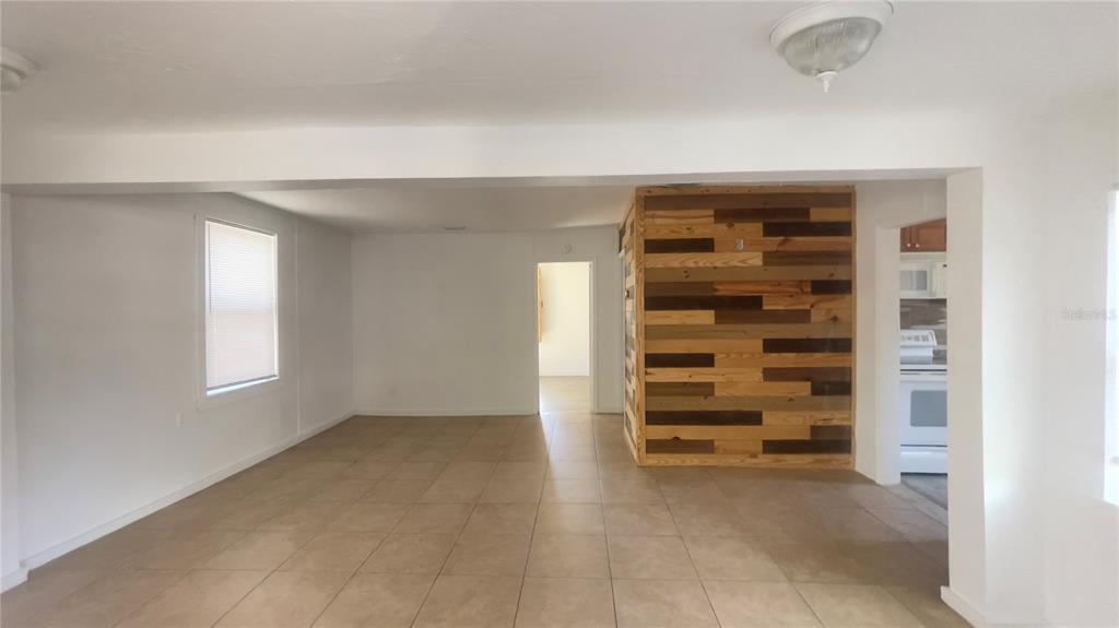 A living room with light-colored tile flooring features a prominent wood-plank accent wall — 432 SE 15TH STREET, GAINESVILLE, FL