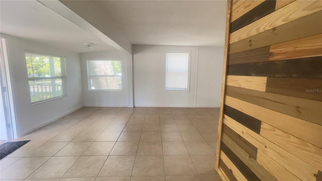 An interior room features light-colored floor tiles and a decorative wood-plank accent wall — 432 SE 15TH STREET, GAINESVILLE, FL