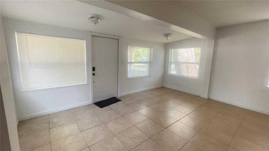 A sunroom with white walls, tiled flooring, a white entry door, and several windows — 432 SE 15TH STREET, GAINESVILLE, FL