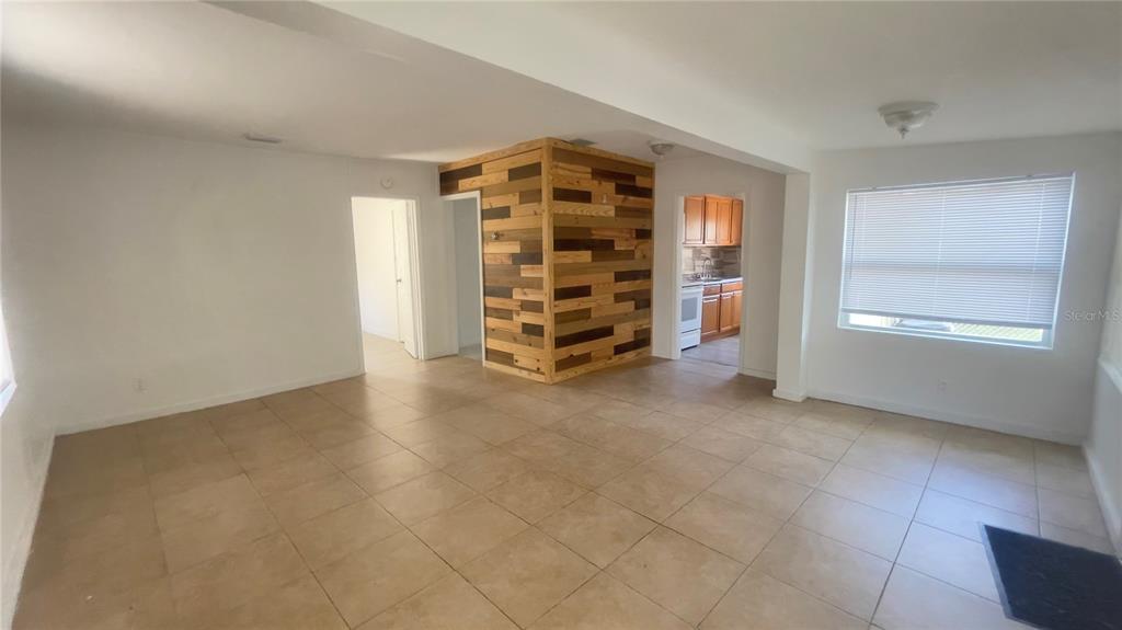 An open living area features tile flooring, white walls, and a wood-paneled accent wall — 432 SE 15TH STREET, GAINESVILLE, FL