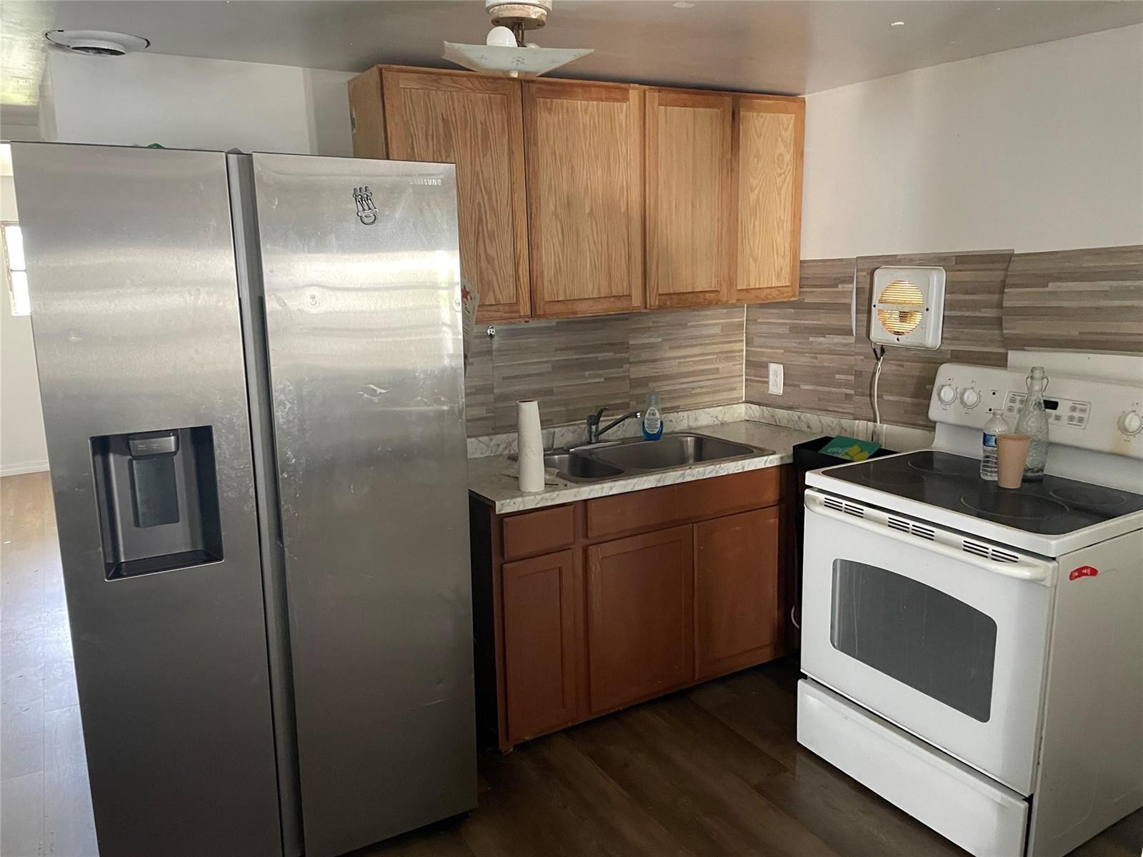 A kitchen features wood cabinets, a stainless steel refrigerator, a white stove, and tiled backsplash — 8508 SW 16th Court, Davie FL 33324, DAVIE, FL