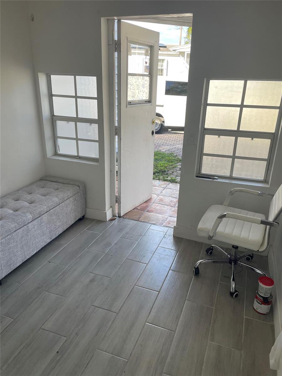 A small room features gray wood-look tile flooring, a tufted bench, and a white office chair — 8508 SW 16th Court, Davie FL 33324, DAVIE, FL