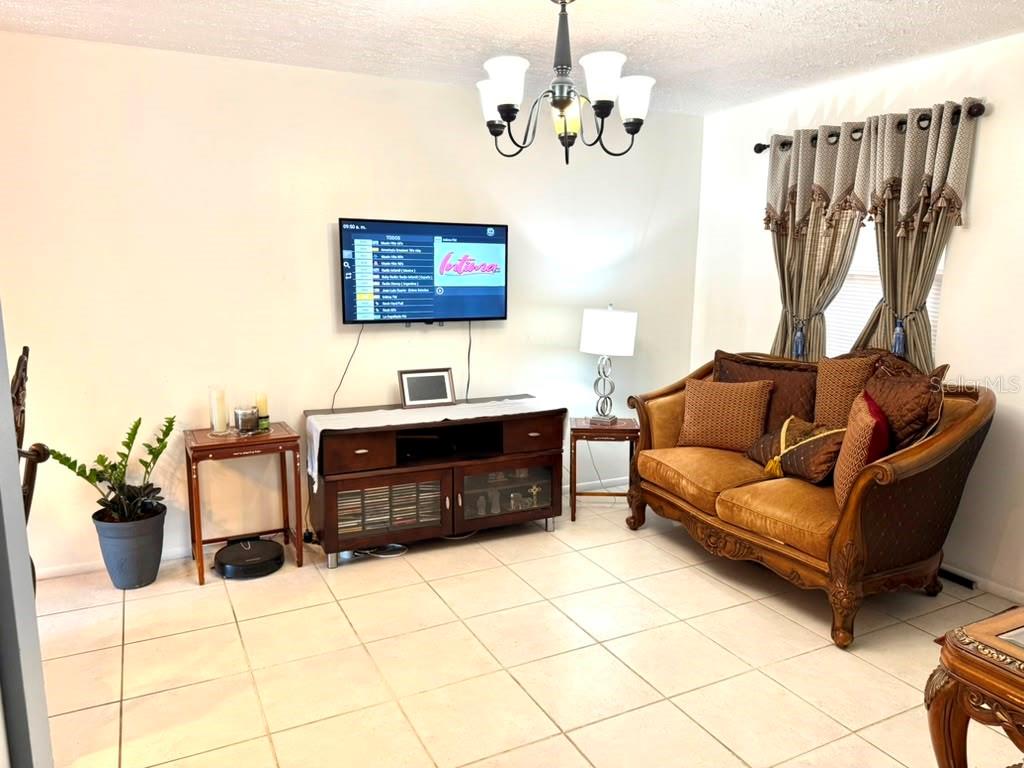 A living room features a brown sofa, a wooden media console, and a wall-mounted television — 69 S MARBRISA WAY, KISSIMMEE, FL