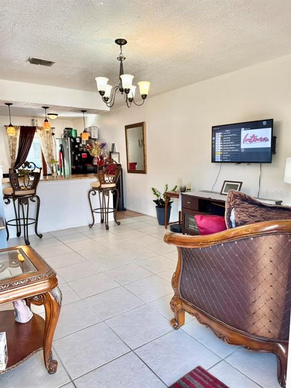 A living room and kitchen area feature tile flooring, a chandelier, and bar seating — 69 S MARBRISA WAY, KISSIMMEE, FL