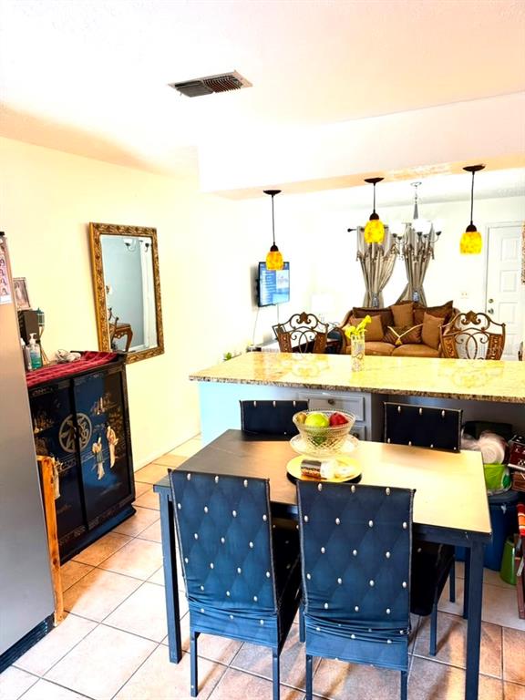 A dining area features a dark table with tufted chairs and a granite-topped kitchen island — 69 S MARBRISA WAY, KISSIMMEE, FL