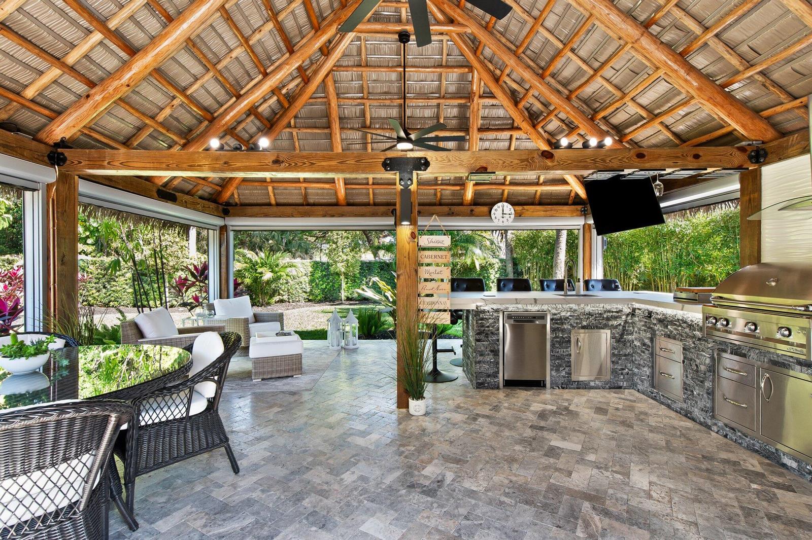 An open-air patio with a thatched roof, stone kitchen island, grill, and outdoor dining area — 110 S Cortez Drive # 110, Margate FL 33068, MARGATE, FL