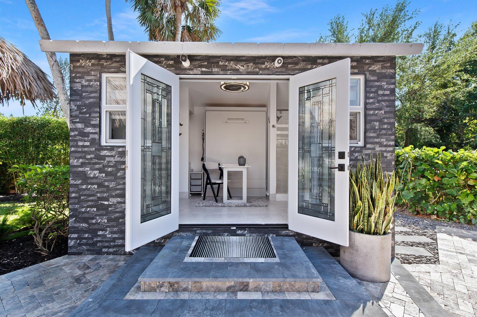 A small detached building with stone-textured siding and glass-paneled double doors opening to a room — 110 S Cortez Drive # 110, Margate FL 33068, MARGATE, FL