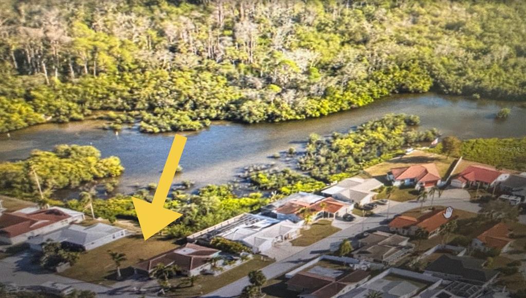 An aerial view shows a residential house with a large backyard bordering a wooded waterway — 3982 RUDDER WAY, NEW PORT RICHEY, FL