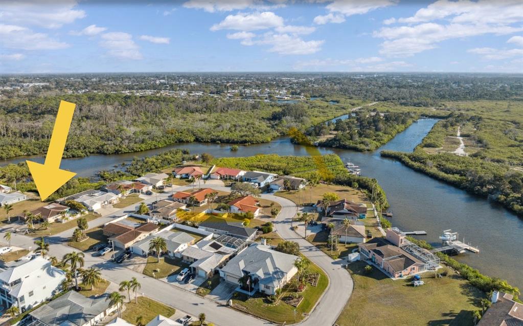 An aerial view shows a residential neighborhood with houses situated near a winding canal — 3982 RUDDER WAY, NEW PORT RICHEY, FL