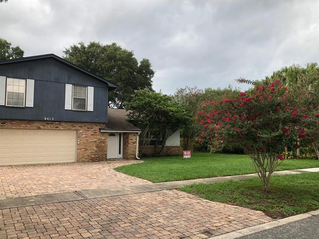A two-story house with a brick and blue siding exterior, a garage, and a front lawn — 8413 SHADY GLEN DRIVE, ORLANDO, FL