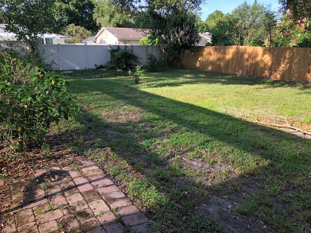 A backyard features a brick patio, a grassy lawn, and wooden and vinyl privacy fences — 8413 SHADY GLEN DRIVE, ORLANDO, FL