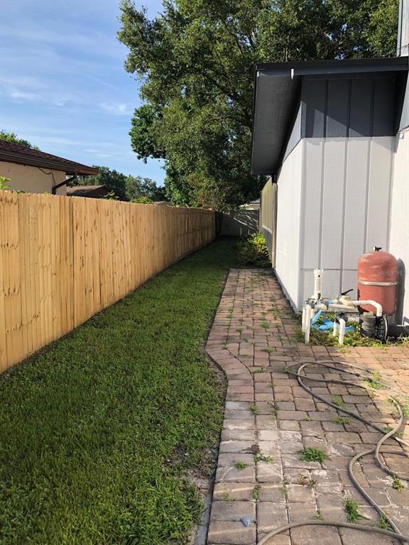 A side yard features a brick walkway, a wooden privacy fence, and pool equipment — 8413 SHADY GLEN DRIVE, ORLANDO, FL