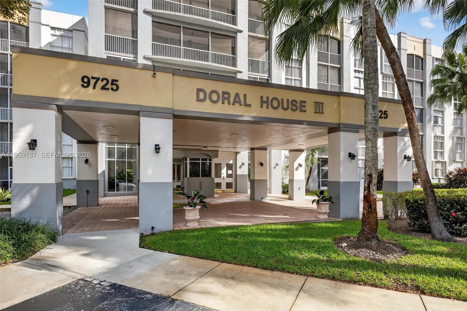 The exterior of a multi-story residential building features a covered entrance with columns and landscaping — 9725 NW 52nd St # 103, Doral FL 33178, DORAL, FL