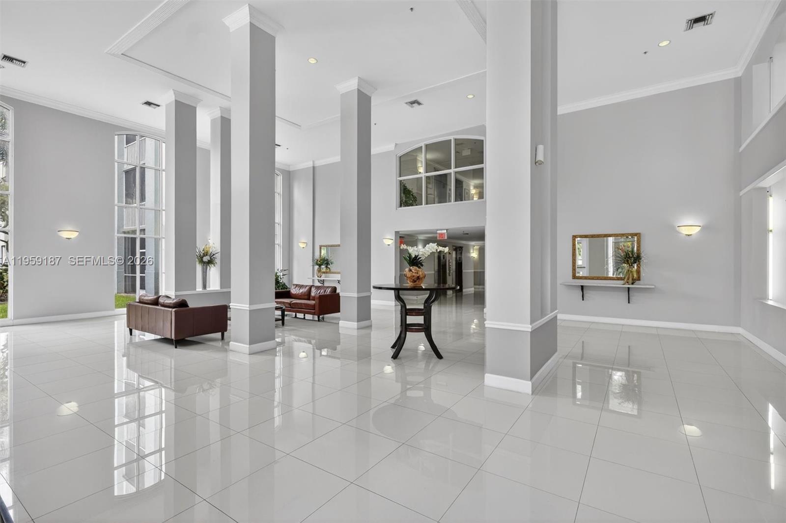 A spacious, high-ceilinged lobby features white tile floors, large support columns, and leather seating — 9725 NW 52nd St # 103, Doral FL 33178, DORAL, FL