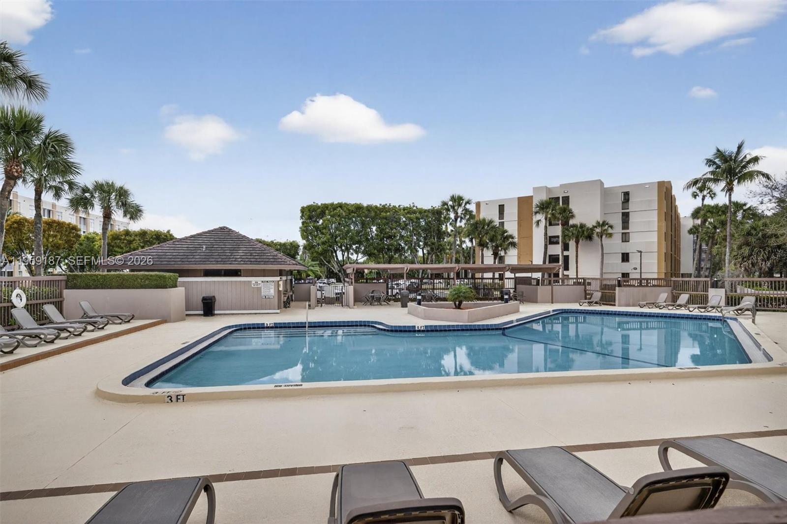 A swimming pool with lounge chairs on a deck sits in front of a building — 9725 NW 52nd St # 103, Doral FL 33178, DORAL, FL