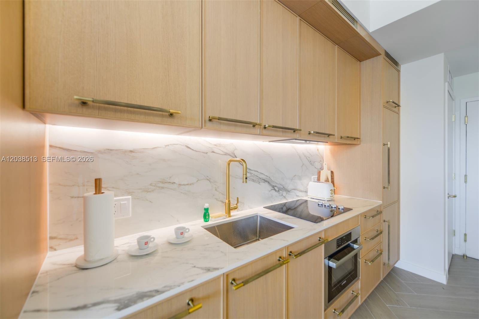 A modern kitchen features light wood cabinets, marble countertops, and gold hardware — 2700 NW 2nd Ave # 509, Miami FL 33127, MIAMI, FL